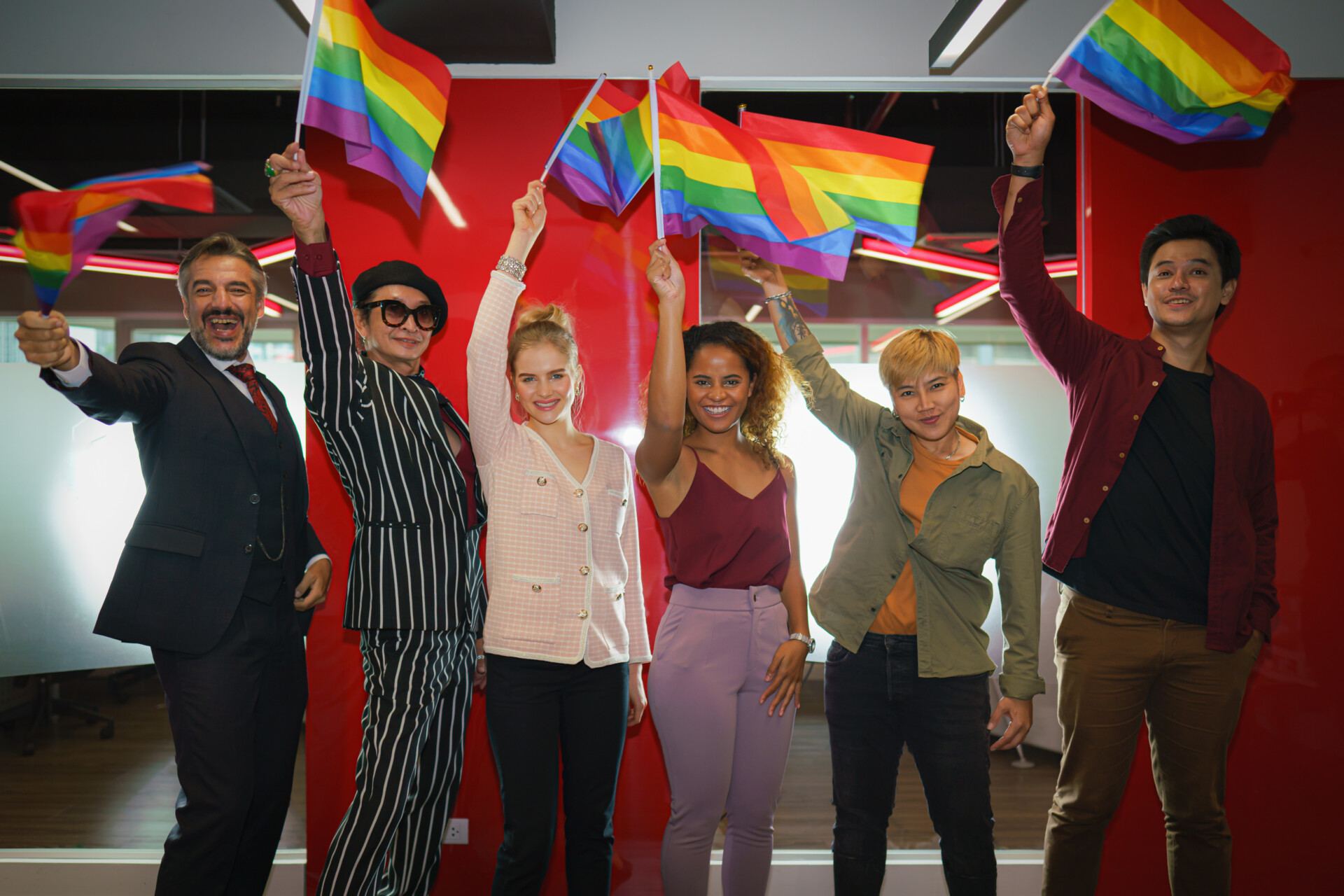 Diverse Group Of Lgbtq People With Rainbow Flag On Hand Team Up diverse group of LGBTQI business people in business office with rainbow flag on hand form up team for LGBTQ campaign movement